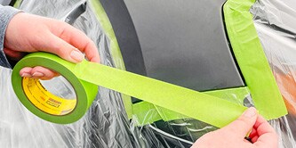 Aufbringen des Klebebands 233+ an der Frontleuchte eines Fahrzeugs
