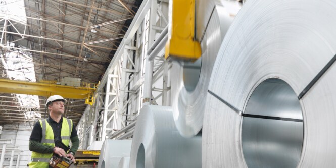 Arbeiter, der Metallblechrollen transportiert
