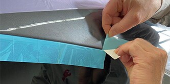 Aufbringen von Perforiertem Lift'n Stick Abdeckband auf Gummifensterdichtungen
