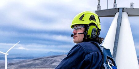 Ein Mann auf einer Windturbine trägt einen Schutzhelm
