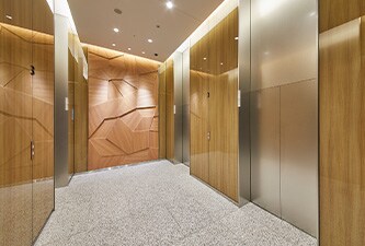 Aufzugshalle mit 3M DI-NOC Oberflächenfinish für Glas mit Holzmaserungen an den Wänden
