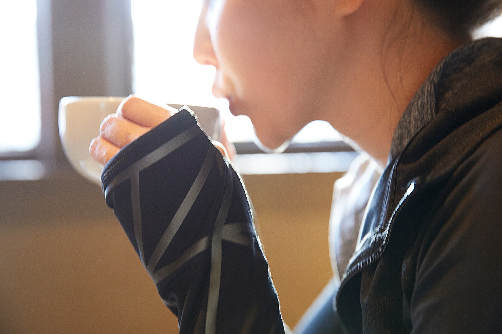 Frau trinkt Kaffee, Großaufnahme von Scotchlite Black Stretch Reflective auf dem Ärmel der Frau mit Kaffee.
