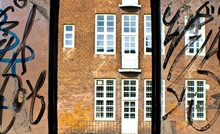 3-Scheiben-Fenster eines Gebäudes. Seitenscheiben mit Graffiti, mittlere Scheibe sauber
