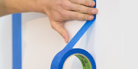 Bild, das eine Person zeigt, die mit 3M Abdeckband Motive an einer Wand malt
