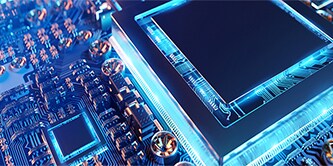 Nahaufnahme einer elektronischen Leiterplatte mit einem Mikrochip in der Mitte, blau beleuchtet 
