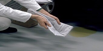 Frau reinigt Arbeitsbereich mit saugstarken Tüchern
