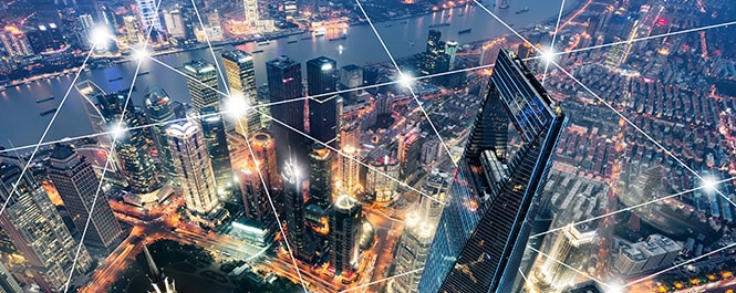 Skyline einer Stadt im Hintergrund, Grafik von mit geraden Linien zu einem geometrischen Muster verbundenen Lichtknotenpunkten im Vordergrund
