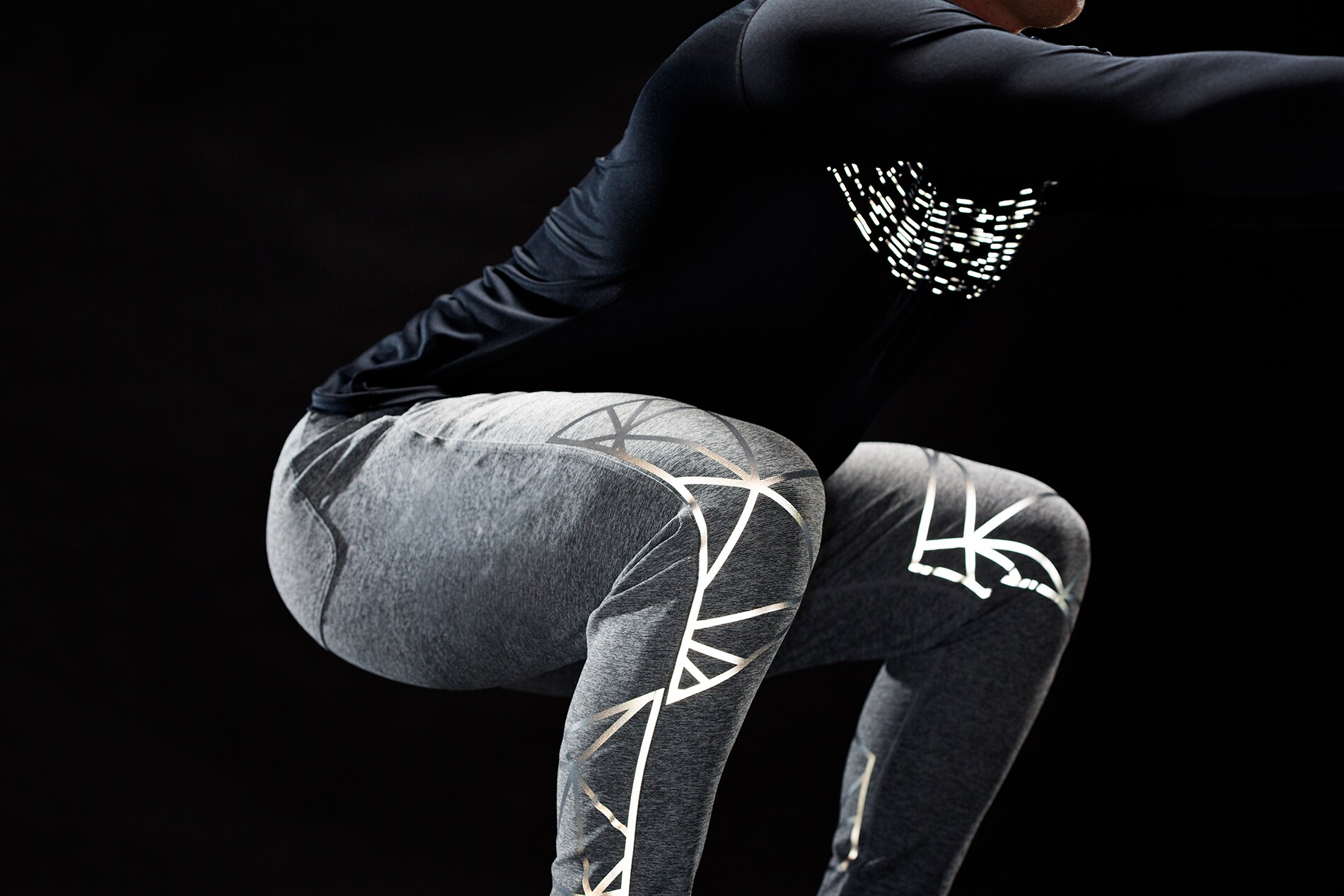 Mann macht Kniebeugen mit beleuchtetem 3M Scotchlite Black Stretch Reflective, das sich über die Knie und Brust dehnt.