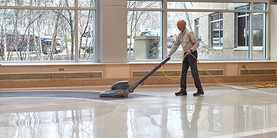 Mann reinigt Boden mit professioneller Reinigungsmaschine
