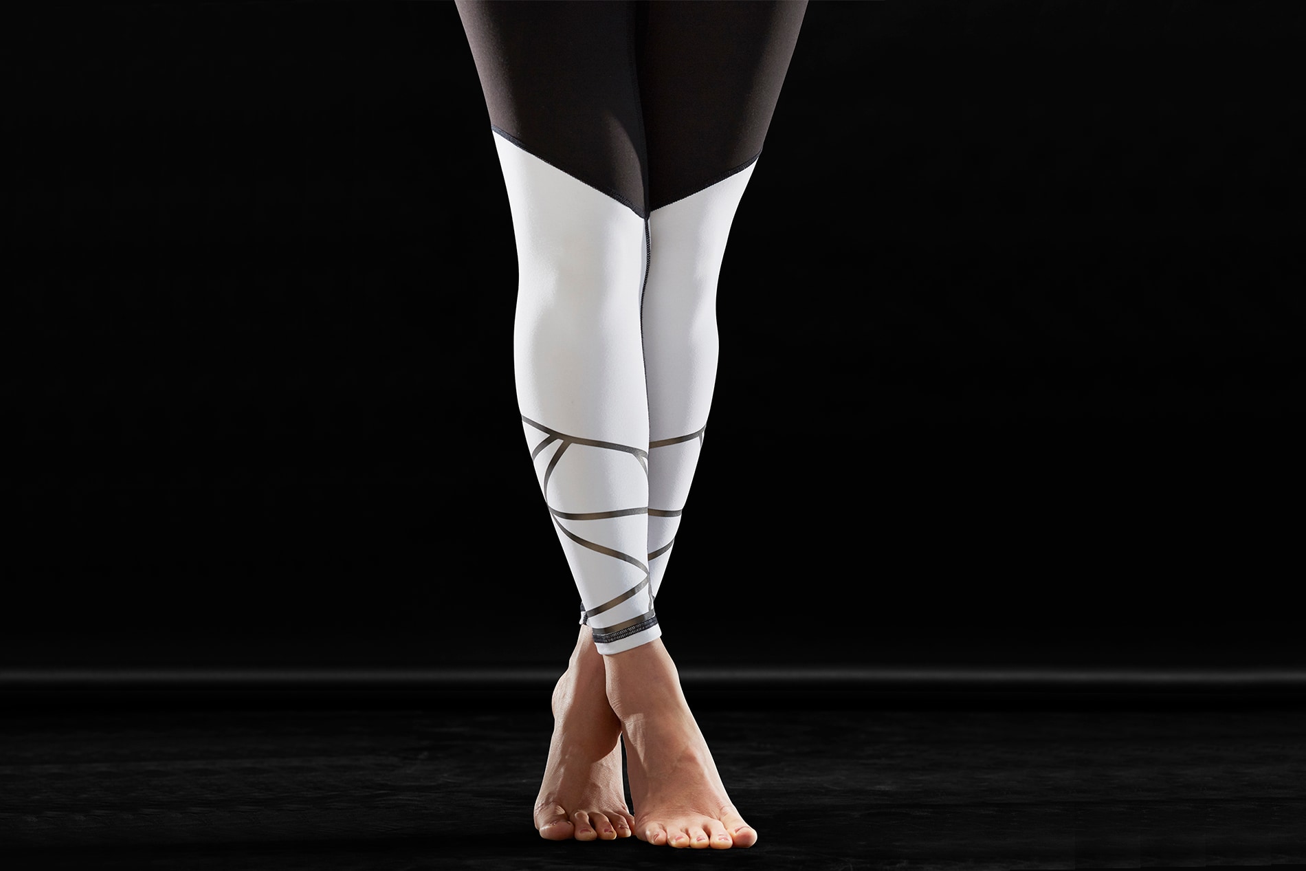Frau trägt weiße Tights mit Scotchlite Black Stretch Reflective und steht auf Zehenspitzen.