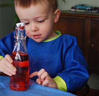 2-year-old William spins a bottle with liquid inside to create a tornado in a bottle.