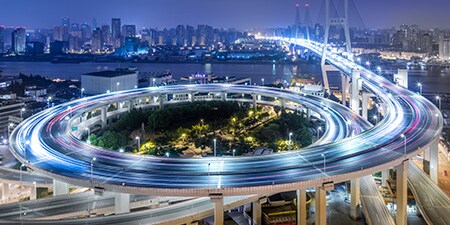 Luftaufnahme einer spiralförmigen Autobahn bei Nacht.
