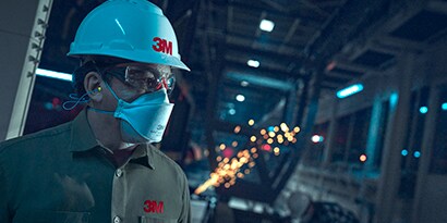 Anwender mit 3M Einweg-Atemschutzmaske und Schutzhelm
