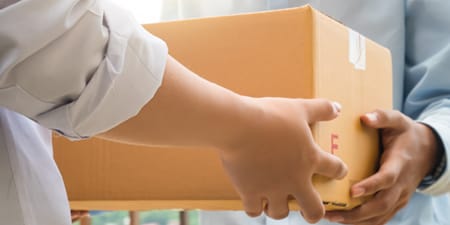 Eine Person, die einen Karton an eine andere Person übergibt.
