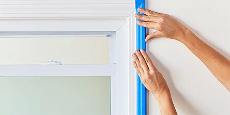 Hände, die zeigen, wie das Klebeband fest auf die Oberfläche gedrückt wird
