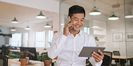 Person hält ein Telefon und ein Tablet und lächelt