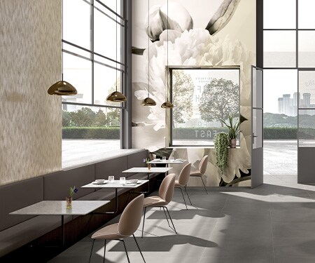 Caféeinrichtung in neutralen Tönen, Wände mit gedruckten Blumenmotiven auf Grafikfolie.
