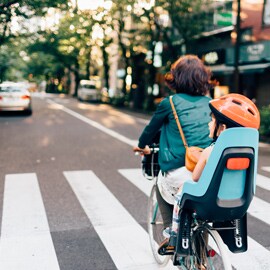 Elternteil und Kind fahren mit dem Fahrrad auf einer Straße