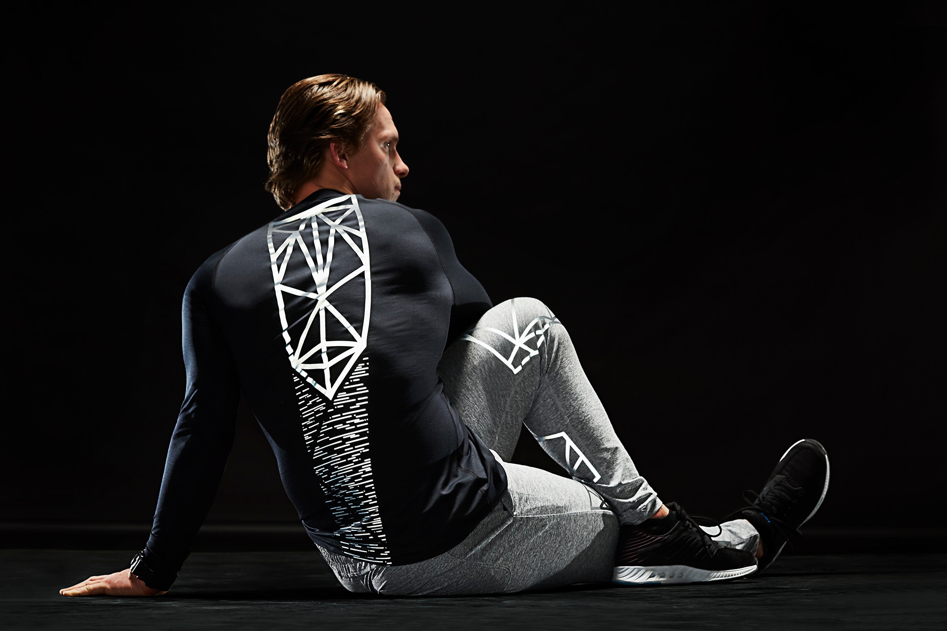 Sportlicher Mann dehnt sich, trägt Sportbekleidung mit beleuchtetem 3M Scotchlite C790 Carbon Black Stretch Reflective Material