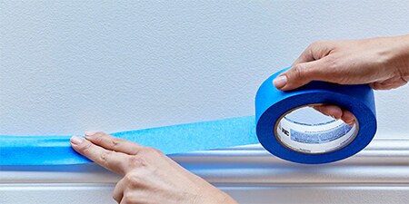 Hände, die zeigen, wie 3M-Abdeckband auf einer Fläche angebracht wird
