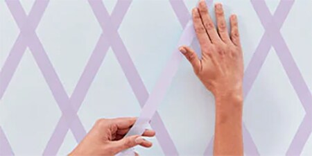 Die Person sorgt dafür, dass das Abdeckband fest an der Wand haftet.
