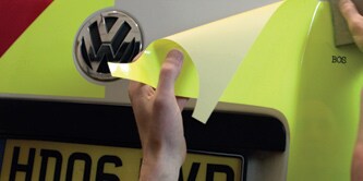 Person, die Chevron-Heckmarkierungen an einem Lieferwagen anbringt
