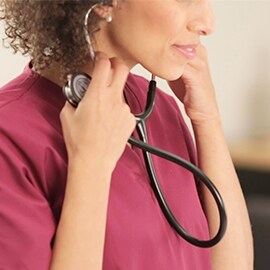 Krankenschwester steckt die Ohroliven ihres 3M Littmann Classic III Stethoskops in ihre Ohren.