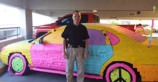 Stuart Littlefield, a police detective in Kansas City, stands in front of his vehicle, his co-workers covered with Post-it Notes in a prank.