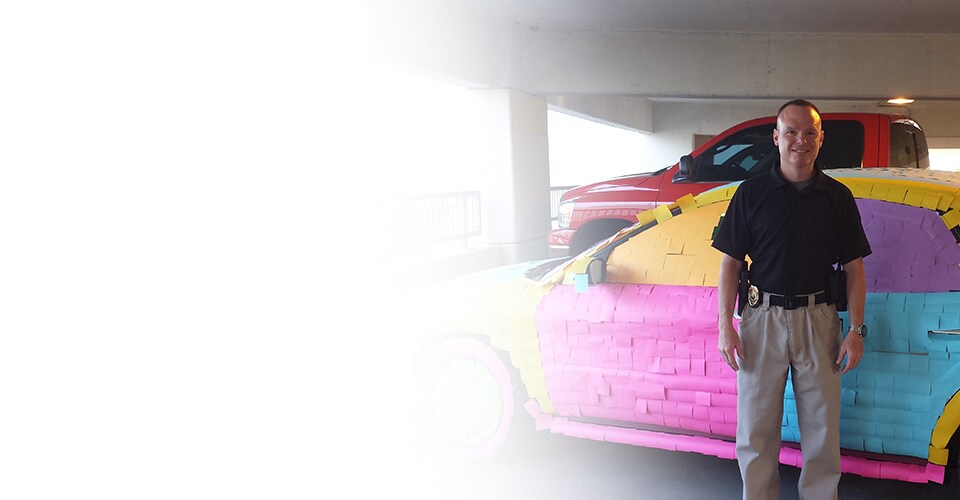 Stuart Littlefield, a police detective in Kansas City, stands in front of his vehicle, his co-workers covered with Post-it Notes in a prank.