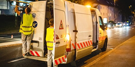 Lieferwagen am Straßenrand mit reflektierenden Chevron-Markierungen
