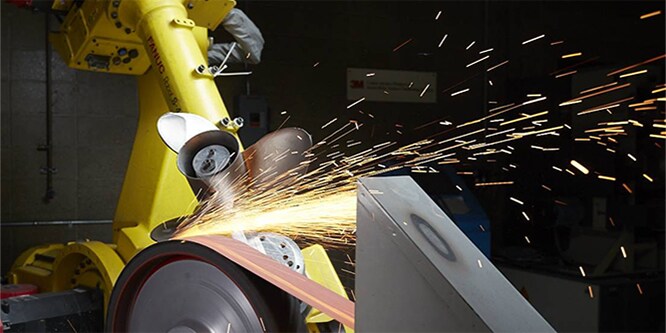 Ein Roboter schleift eine Schiffschraube mit einem Schleifband
