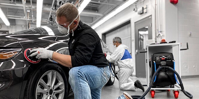 Bild zeigt einen Mann, der hochwertige Schleifmittel und Werkzeuge an einem Auto verwendet, um hervorragende Ergebnisse zu erzielen.
