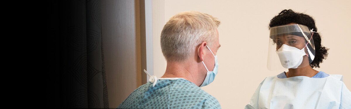 Patient und Krankenschwester tragen Schutzausrüstung
