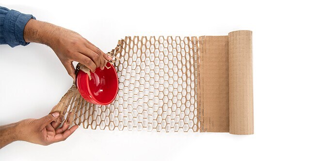 Person, die einen Gegenstand in Scotch Cushion Lock Schutzpapier einwickelt
