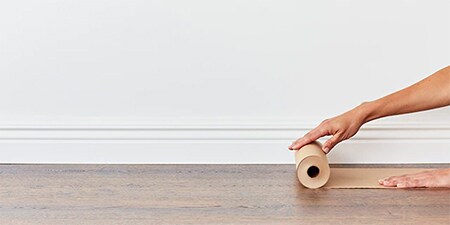 Person, die den Holzboden mit Kolophoniumpapier abdeckt, um ihn zu schützen.
