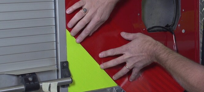  Person, die Reflexfolien an einem Feuerwehrfahrzeug anbringt
