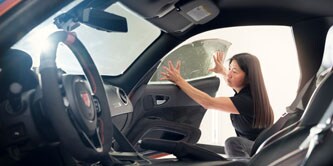Frau bringt Fensterfolie auf einem Auto an
