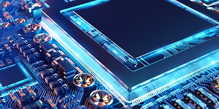 Nahaufnahme einer elektronischen Leiterplatte mit einem Mikrochip in der Mitte, blau beleuchtet 
