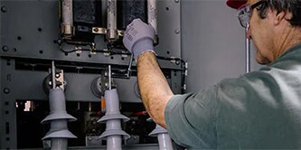 Ein Mann überwacht elektrische Komponenten, um die Zuverlässigkeit des Netzes sicherzustellen.
