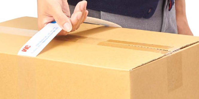 Nahaufnahme der Hand einer Person, die einen Karton an einem Griff hält
