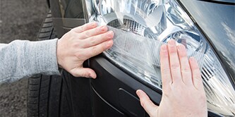 Person, die Scotch® Extremium™ Gewebe- und Reparaturband vorne an einem Auto verwendet
