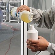 Mann mischt Flüssigseife mit Wasser in einer Sprühflasche