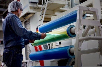 Bild eines Arbeiters, der eine Flexodruckplatte von einem Klebeband auf einem Zylinder entfernt

