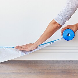 ScotchBlue™ Abdeckfolie wird zur Verwendung auf einer Sockelleiste gezogen und gedehnt