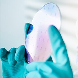 Eine Person hält einen Halbleiter-Wafer gegen das Licht.