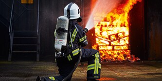 Feuerwehrmann, der an der Leiter eines brennenden Hauses hochklettert
