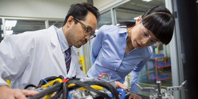 3M Industrial Community. Bild zweier Ingenieure, die in einem Labor Robotikbauteile untersuchen
