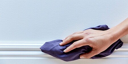 Hände, die mit einem Tuch eine Fläche reinigen, damit das 3M-Klebeband sicher haftet
