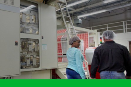Arbeiter gehen an einer Flexodruckmaschine vorbei
