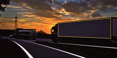 LKW auf einer dunklen Straße mit sichtbaren Konturmarkierungen
